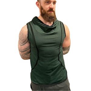 May include: A sleeveless, dark green hooded top with black trim. The top features a cowl neck and a relaxed fit. The garment is made of a soft, textured fabric. The model is wearing gray shorts.