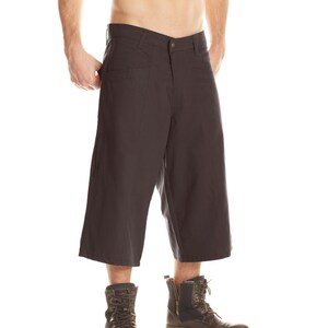 May include: A pair of dark gray cuffed pants with a zipper fly and button closure. The pants are worn by a person wearing brown leather boots.