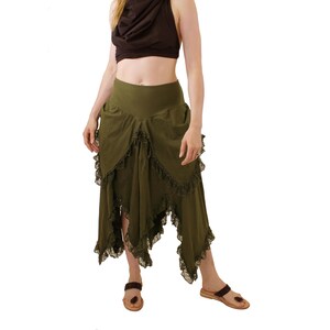 Puede incluir: Una mujer con una blusa negra con capucha y una falda verde de capas con ribete de encaje. La falda es asim&eacute;trica y tiene un dise&ntilde;o fluido.