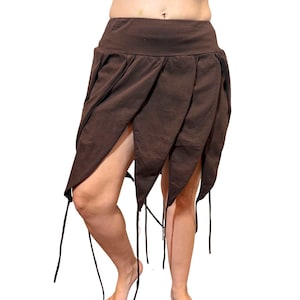 May include: A brown skirt with a unique petal-like design. The skirt features a high waist and asymmetrical hemline with pointed edges. Black drawstrings hang from the hem. The skirt is made of a soft, flowing fabric.