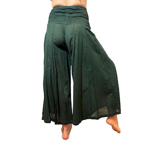 May include: Dark green palazzo pants with a smocked waistband. The wide-leg pants are made of a lightweight fabric. The pants are shown against a white background.