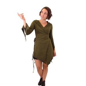 Puede incluir: Un vestido verde de envoltura con capucha, mangas largas y un lazo en la cintura. El vestido tiene un dobladillo asimétrico y está hecho de una tela suave y fluida.
