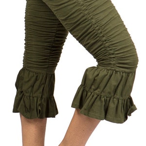 May include: Olive green capri leggings with a ruffled hem. The leggings are made of a soft, stretchy fabric and have a comfortable fit.