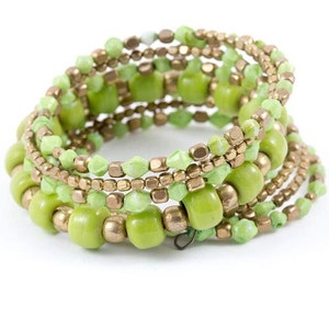 Puede incluir: Un brazalete multicadena hecho de cuentas verdes y doradas. El brazalete está hecho de varias capas de cuentas pequeñas y cuentas redondas más grandes.