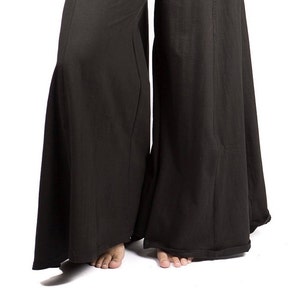 May include: Black wide-leg pants with a wide, flowing silhouette. The pants have a simple design and a comfortable fit.