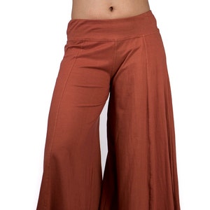 May include: Wide-leg pants in a rust brown color. The pants have a wide, flowing silhouette and a comfortable, relaxed fit.