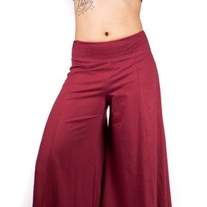 May include: Wide-leg pants in a deep burgundy color. The pants have a high waist and a flowing, loose fit.