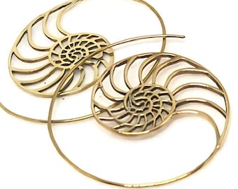 May include: A pair of gold-colored spiral earrings. Each earring features a nautilus shell design at the center, with a detailed, openwork pattern. The earrings are set against a white background.