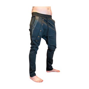 Puede incluir: Pantalones de color verde azulado oscuro con un dise&ntilde;o &uacute;nico. Los pantalones presentan una parte delantera abotonada, una cintura con cord&oacute;n y tela estampada decorativa a lo largo de los bolsillos. Los pantalones tienen un corte ajustado en las piernas.
