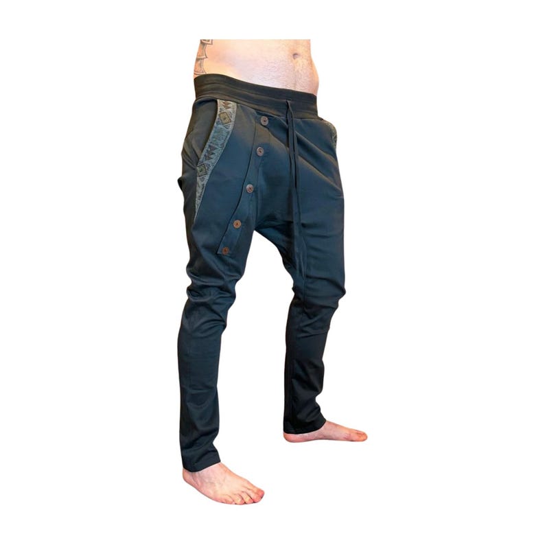 Puede incluir: Pantalones de color verde azulado oscuro con un dise&ntilde;o &uacute;nico. Los pantalones presentan una parte delantera abotonada, una cintura con cord&oacute;n y tela estampada decorativa a lo largo de los bolsillos. Los pantalones tienen un corte ajustado en las piernas.