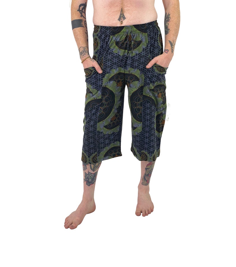 May include: Black and green patterned pants with a drawstring waist and pockets. The pants have a geometric design with a flower of life pattern.