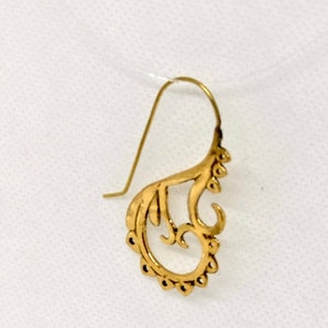 May include: A gold-colored earring with a delicate, intricate design. The earring is shaped like a stylized flower or leaf, with a curved, openwork pattern.