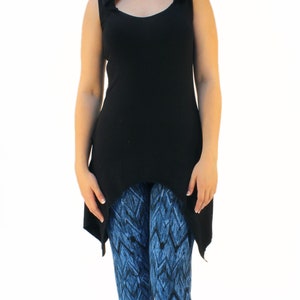 May include: A black sleeveless top with a hood and a high-low hemline. The top is paired with blue and black patterned leggings.