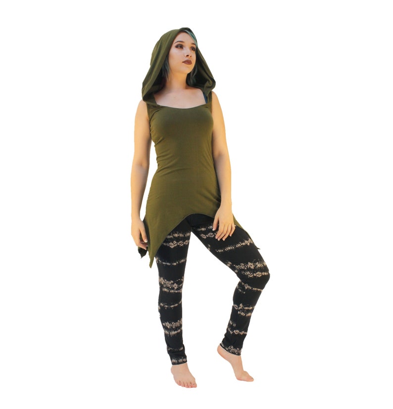 May include: A woman wearing a green hooded top with a long, asymmetrical hemline and black leggings with a white pattern.