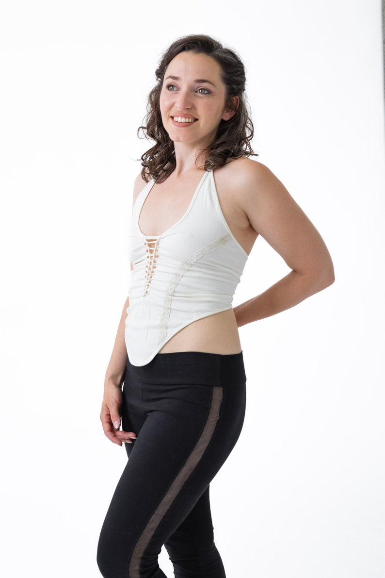 May include: A woman wearing a white halter top with a lace design and black leggings with a mesh panel on the side.