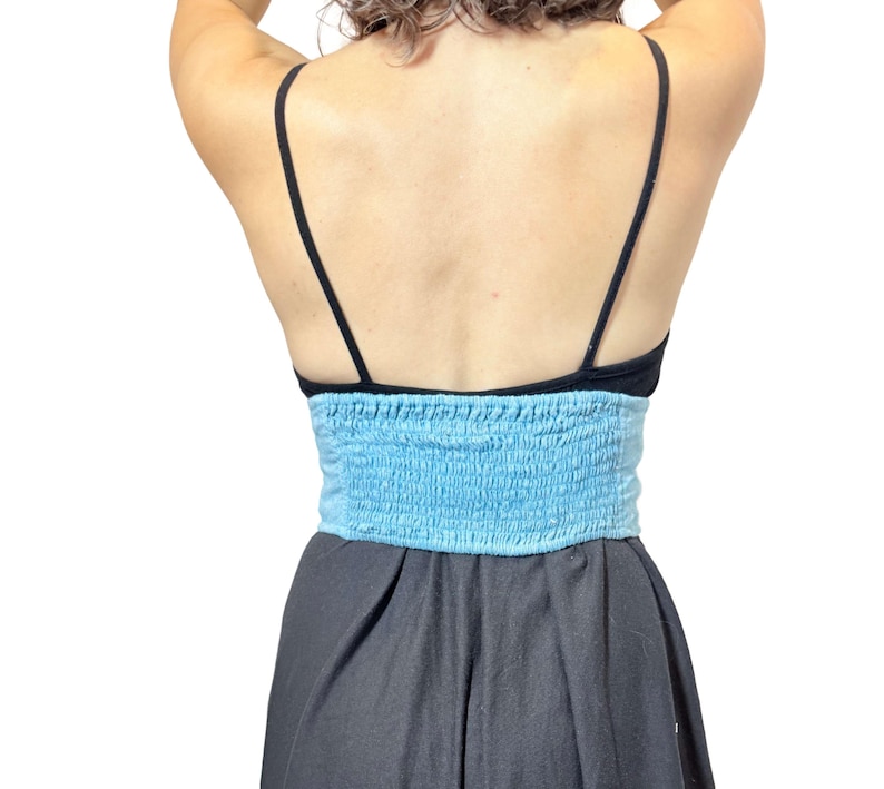 May include: A black top with thin straps and a light blue, smocked bandeau-style top. The bottom portion of the outfit is a dark gray, flowing skirt. The outfit is shown from the back.