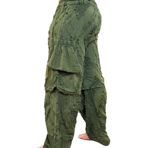 Op de afbeelding: Olijfgroene broek met een uniek, getextureerd ontwerp. De broek heeft een relaxte pasvorm met meerdere zakken en een taille met trekkoord. De stof heeft een distressed uitstraling, wat bijdraagt aan de casual stijl. Ontworpen voor comfort en een bohemien esthetiek.