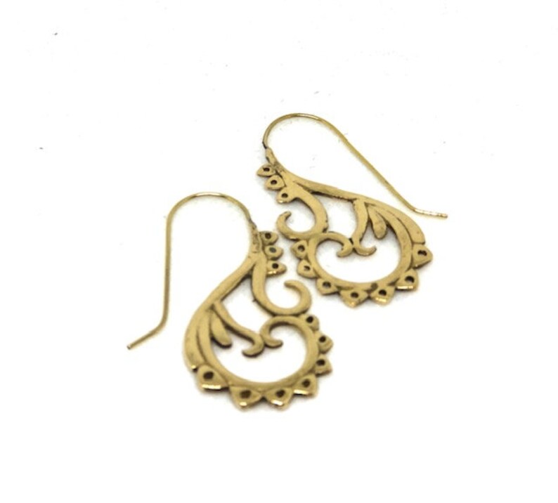 May include: A pair of gold filigree dangle earrings with a delicate, intricate design. The earrings are made of metal and have a hook closure.