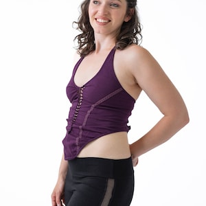 May include: A woman wearing a purple halter top with a lace trim and black leggings with mesh panels.