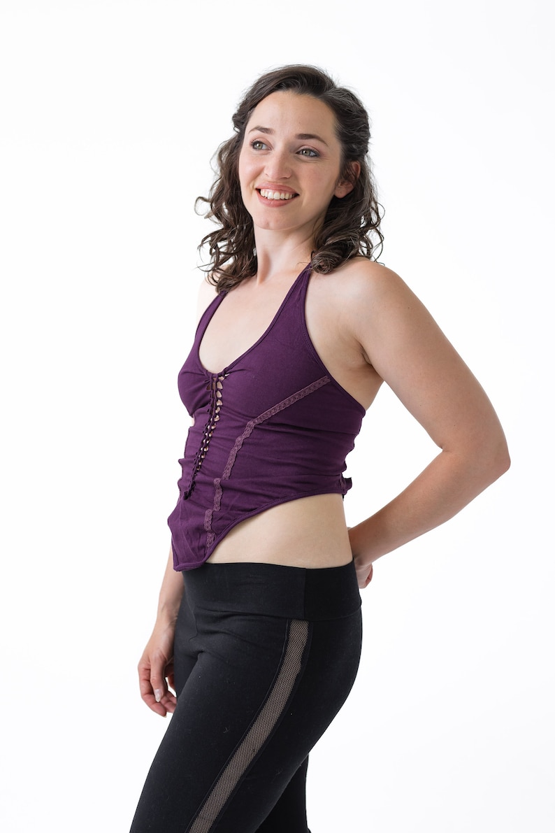 May include: A woman wearing a purple halter top with a lace trim and black leggings with mesh panels.