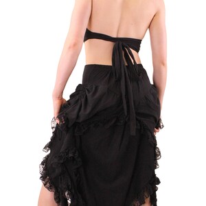 Puede incluir: Una camiseta negra con capucha y una falda negra con un dobladillo con volantes y ribete de encaje. La falda est&aacute; atada a la cintura con una cinta negra.