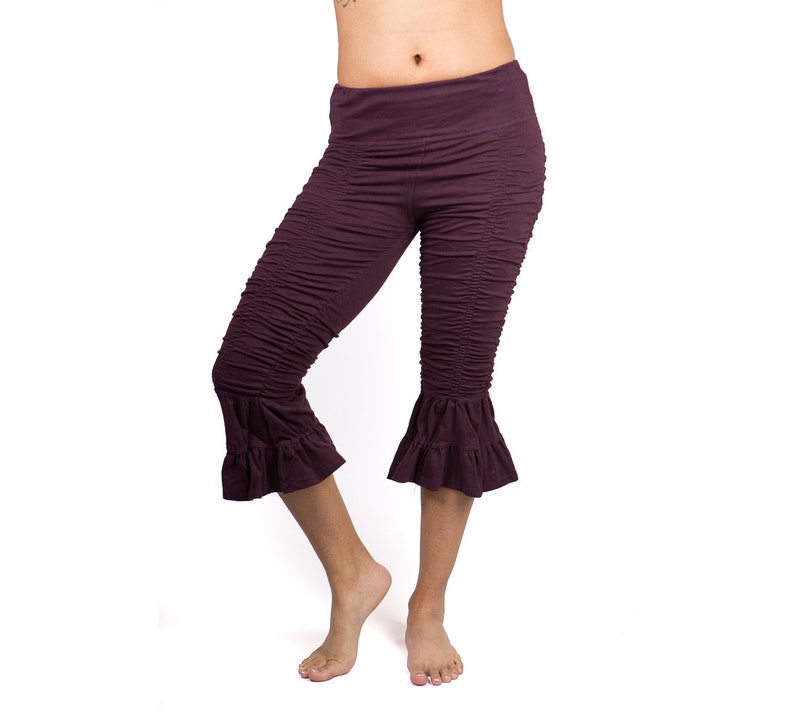 May include: A pair of purple cropped pants with a ruffled hem. The pants are made of a soft, stretchy fabric and have a comfortable fit.