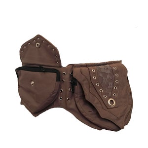 May include: A brown canvas belt with multiple pockets and a lace accent. The belt has metal eyelets and a zipper closure.