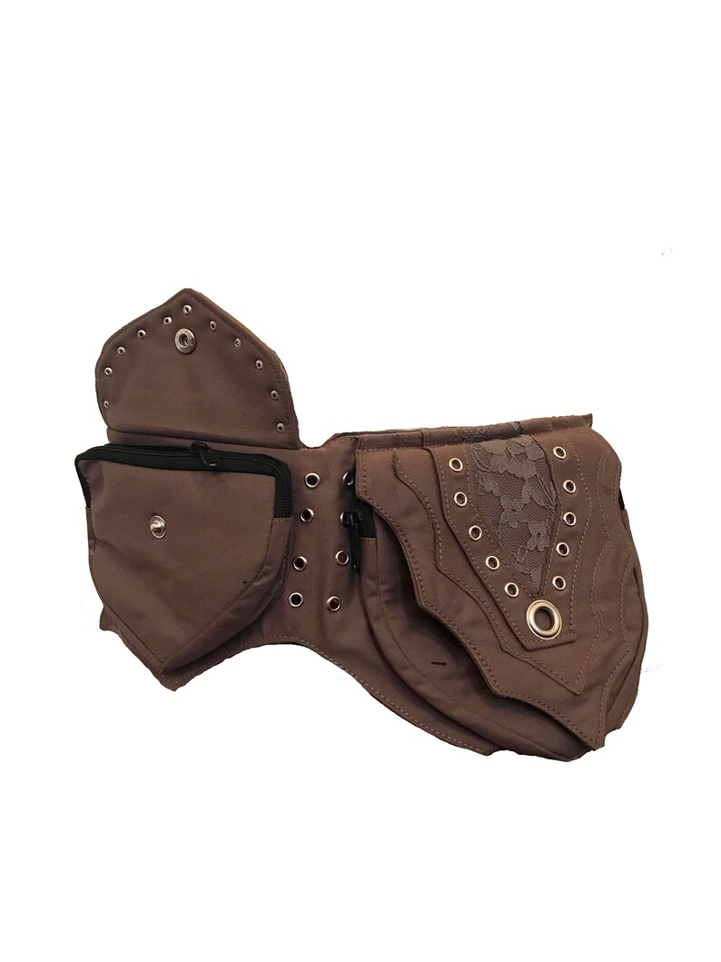 May include: A brown canvas belt with multiple pockets and a lace accent. The belt has metal eyelets and a zipper closure.