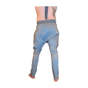 Puede incluir: Pantalones har&eacute;n de color azul claro con un ajuste relajado y cintura el&aacute;stica. Los pantalones tienen una entrepierna baja y perneras estrechas. La tela parece ser un material ligero, adecuado para ropa informal. Los pantalones se muestran desde atr&aacute;s.