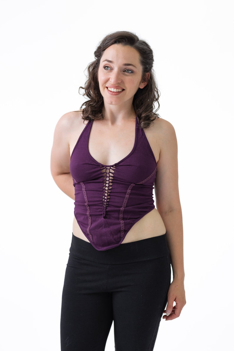 May include: A woman wearing a purple halter top with a lace-up detail and black pants.