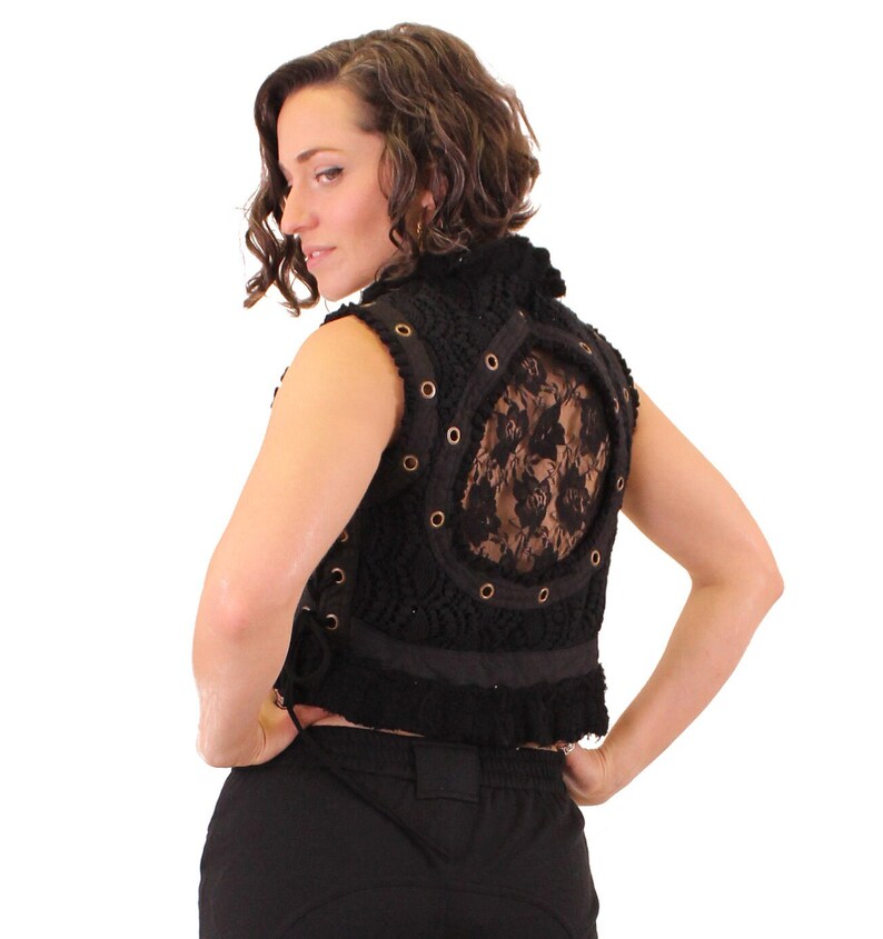 Op de afbeelding: Zwarte, mouwloze vest met een gehaakt ontwerp en een kantpaneel op de rug. De vest heeft een hoge halslijn en een gerimpelde zoom.