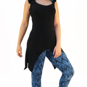 May include: A black hooded top with a long, asymmetrical hemline. The top is paired with blue and black patterned leggings.