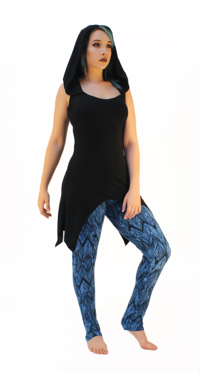 May include: A black hooded top with a long, asymmetrical hemline. The top is paired with blue and black patterned leggings.