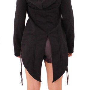 May include: A black hooded jacket with a long, flowing back and a split hem. The jacket has a drawstring at the waist and is made of a soft, comfortable fabric.
