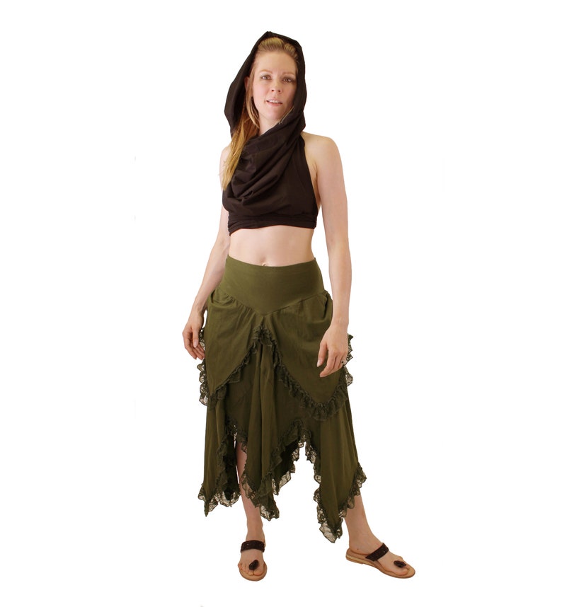 Puede incluir: Una mujer con una blusa negra con capucha y una falda verde de capas con ribete de encaje. La falda es asim&eacute;trica y tiene un dise&ntilde;o fluido.