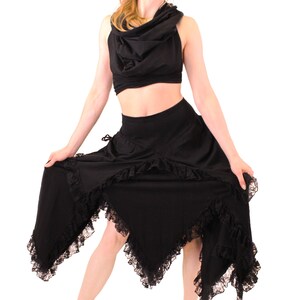 Puede incluir: Una falda negra asim&eacute;trica con ribete de encaje y un top negro con cuello de pico.