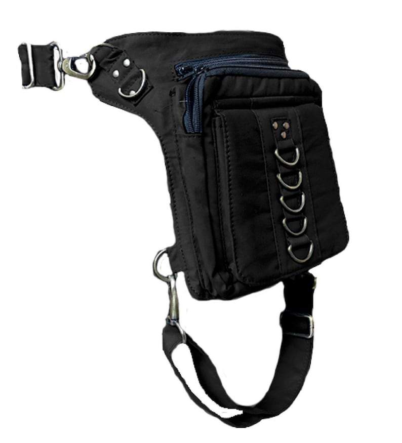 May include: Black canvas thigh bag with multiple pockets and a strap that goes around the leg. The bag has a zipper closure and metal accents.