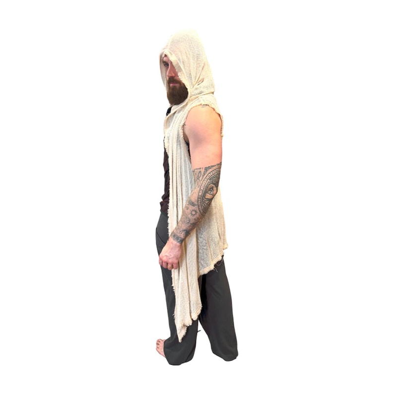 May include: A sleeveless, hooded vest in a light beige color. The vest has a draped, asymmetrical design with a raw hem. The garment is made of a lightweight, textured fabric. The model is wearing dark gray pants.