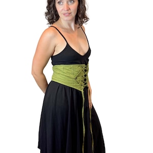 May include: A black dress with a green corset-style belt. The belt is a light green color and features a lace-up design in the front. The dress has a simple, sleeveless top and a flowing skirt.
