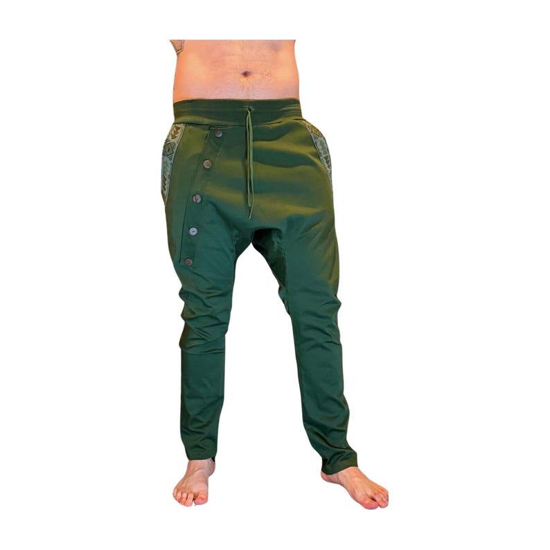 Puede incluir: Pantalones verdes de estilo har&eacute;n con cierre lateral abotonado y cintura con cord&oacute;n. Los pantalones tienen un corte holgado en las caderas y una pernera entallada. La tela es de color liso, con un panel estampado en el lateral.