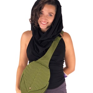 May include: A woman wearing a black cowl neck top and a black scarf is carrying a green leaf-shaped crossbody bag with a quilted design.
