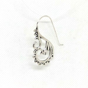 May include: Silver dangle earring with a delicate, ornate design featuring a swirl pattern.