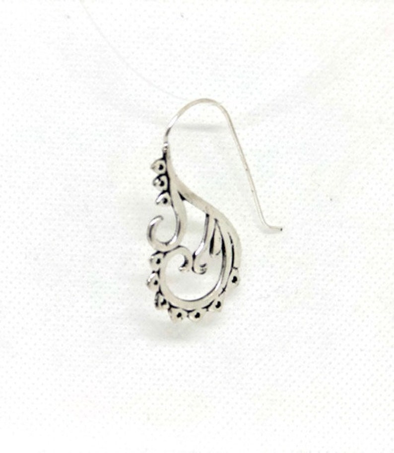 May include: Silver dangle earring with a delicate, ornate design featuring a swirl pattern.