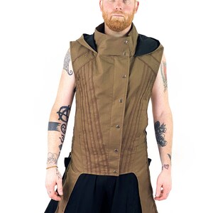 K&ouml;nnte beinhalten: Eine braune &auml;rmellose Weste mit hohem Kragen und einer schwarzen Kapuze. Die Weste hat einen langen, spitzen Saum und wird mit Kn&ouml;pfen geschlossen. Die Weste ist aus einem strukturierten Stoff gefertigt und hat einen l&auml;ssigen, entspannten Stil.