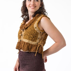 Op de afbeelding: Een vrouw draagt een bruin gehaakt vest met een vetersluiting en een bruine rok.