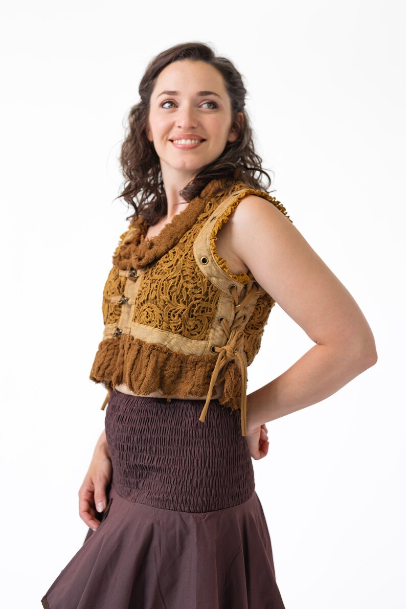 Op de afbeelding: Een vrouw draagt een bruin gehaakt vest met een vetersluiting en een bruine rok.