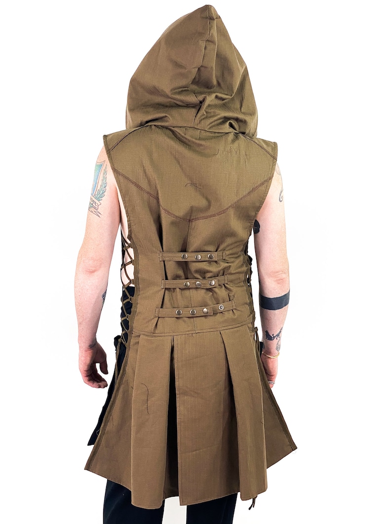 K&ouml;nnte beinhalten: Eine braune &auml;rmellose Kapuzenweste mit einem langen, flie&szlig;enden Rock. Die Weste hat einen Schn&uuml;rr&uuml;cken mit Metallverzierungen und eine Kordelzugtaille.