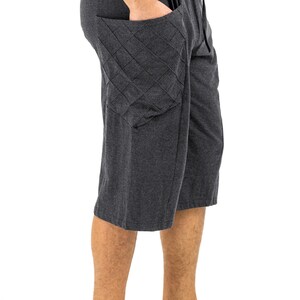 May include: A pair of dark gray, knee-length shorts with a large, quilted pocket on the left side. The shorts have a drawstring waistband.