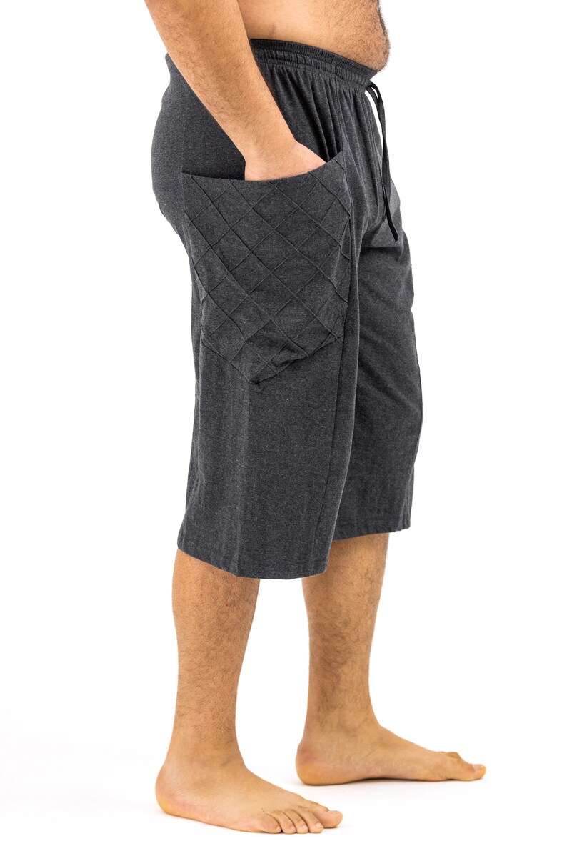 May include: A pair of dark gray, knee-length shorts with a large, quilted pocket on the left side. The shorts have a drawstring waistband.