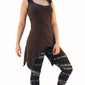 May include: A brown sleeveless hooded top with a high low hemline. The model is wearing black leggings with a white floral pattern.